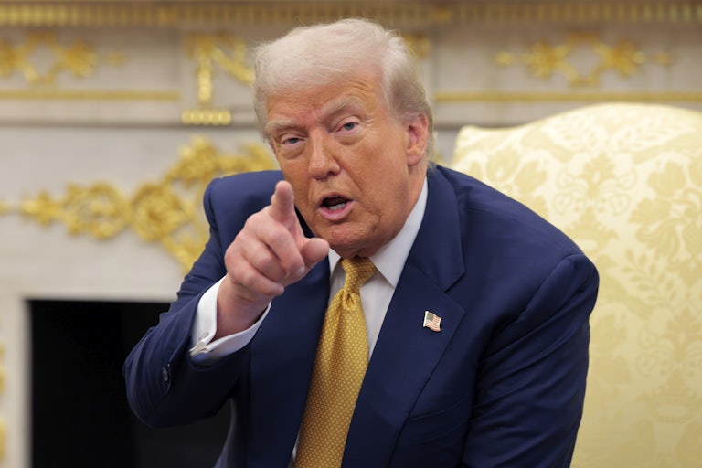 Donald Trump points and speaks while seated in the Oval Office of the White House.