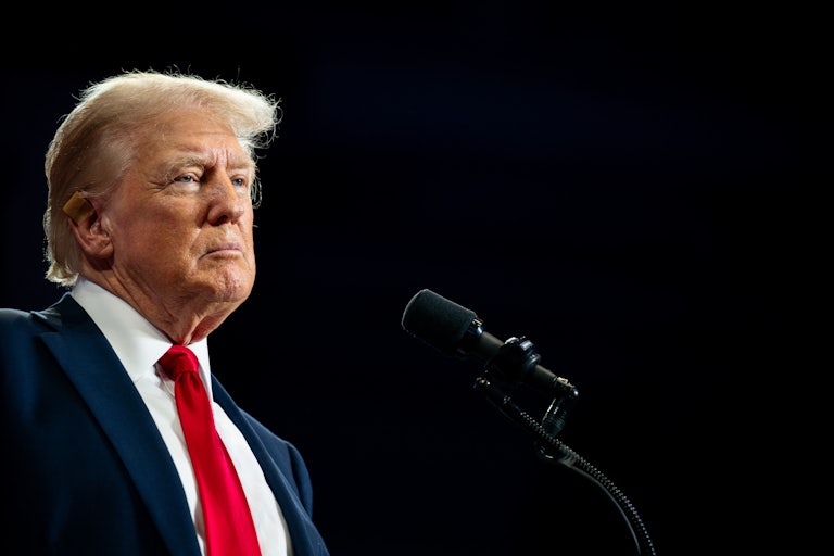Donald Trump stares off grimly into space, as a mic is before him