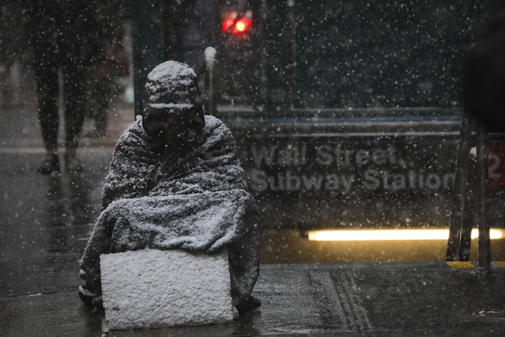 A homeless man sits in the falling snow in New York’s financial district