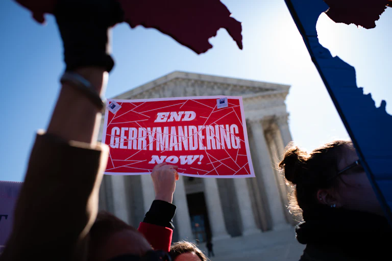Someone holds a sign reading "End Gerrymandering Now!" in front of the Supreme Court.