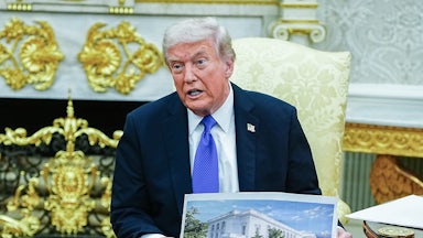 Donald Trump speaks and holds up renderings of his ballroom while sitting in the Oval Office