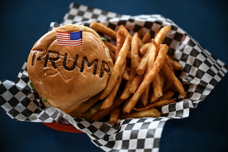 A burger stamped with "Trump" and a tiny U.S. flag on a toothpick sits in a basket with fries.