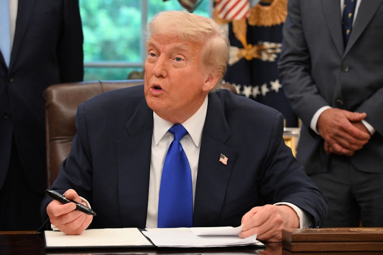 Donald Trump looks up while signing an executive order in the White House