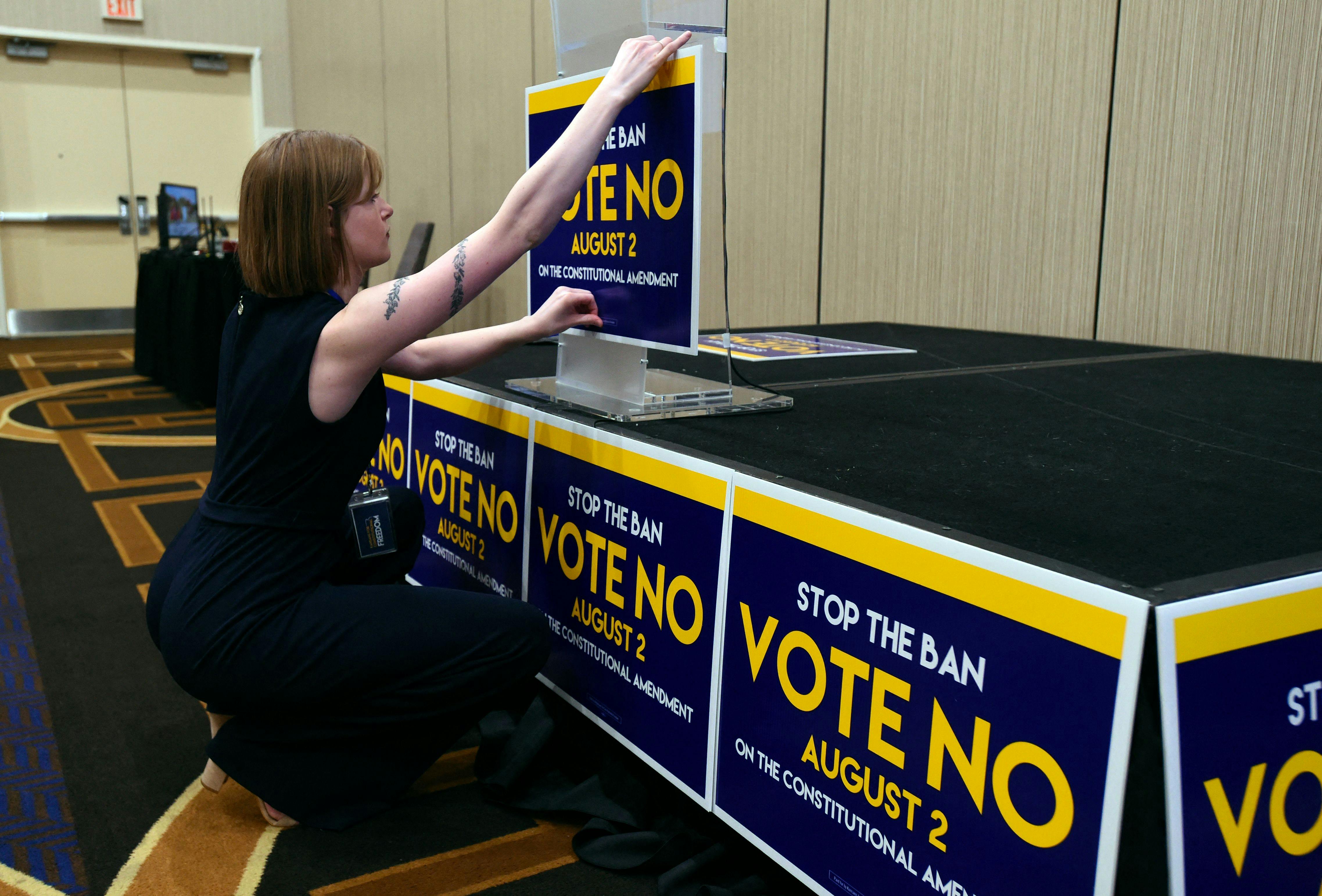 Field organizer Jae Grey places signs on the podium before the pro-choice Kansas for Constitutional Freedom primary election watch party on August 2, 2022.