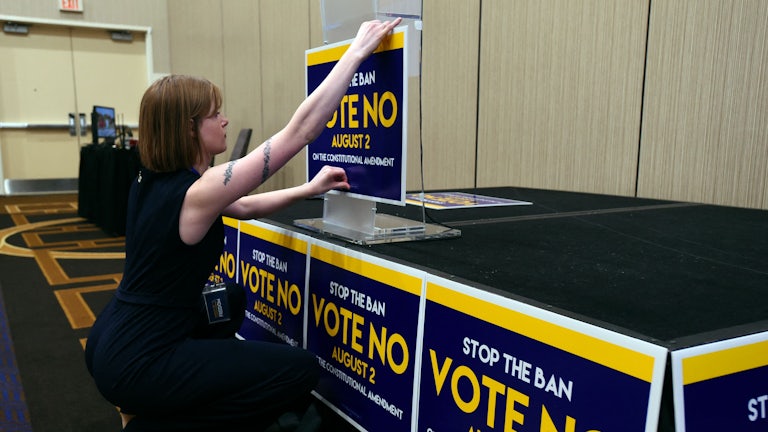 Field organizer Jae Grey places signs on the podium before the pro-choice Kansas for Constitutional Freedom primary election watch party on August 2, 2022.
