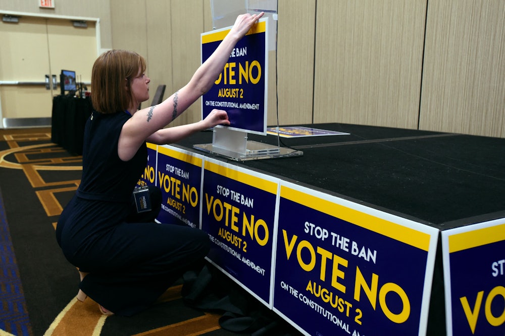 Field organizer Jae Grey places signs on the podium before the pro-choice Kansas for Constitutional Freedom primary election watch party on August 2, 2022.