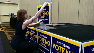 Field organizer Jae Grey places signs on the podium before the pro-choice Kansas for Constitutional Freedom primary election watch party on August 2, 2022.