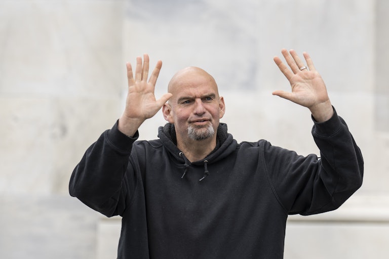 John Fetterman raises both hands up as if in greeting (or surrender)
