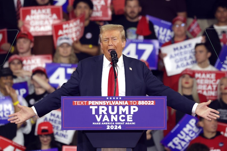 Donald Trump holds his arms out while speaking at a podium during a campaign event