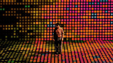 An illustration of a man standing on a stage of computer pixels