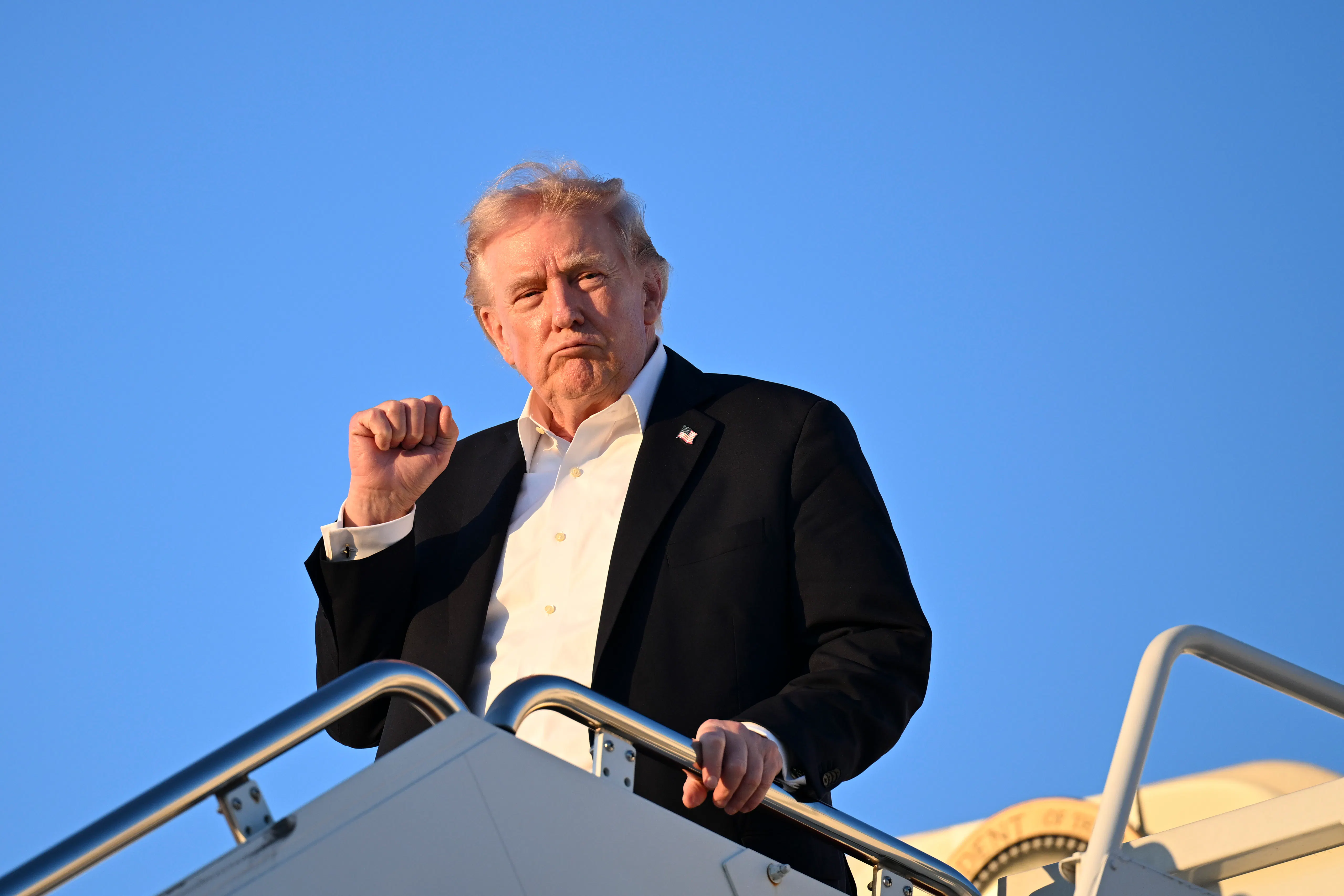 Donald Trump holds right fist up while exiting Air Force One