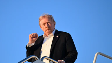 Donald Trump holds right fist up while exiting Air Force One