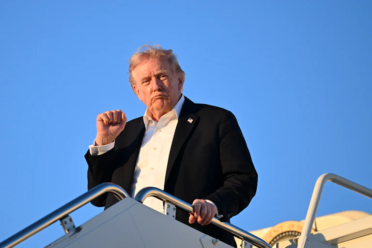 Donald Trump holds his right fist up while exiting Air Force One