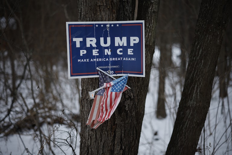 Trump Pence Make America Great Again Sign nailed to a tree along with two small U.S. flags below them
