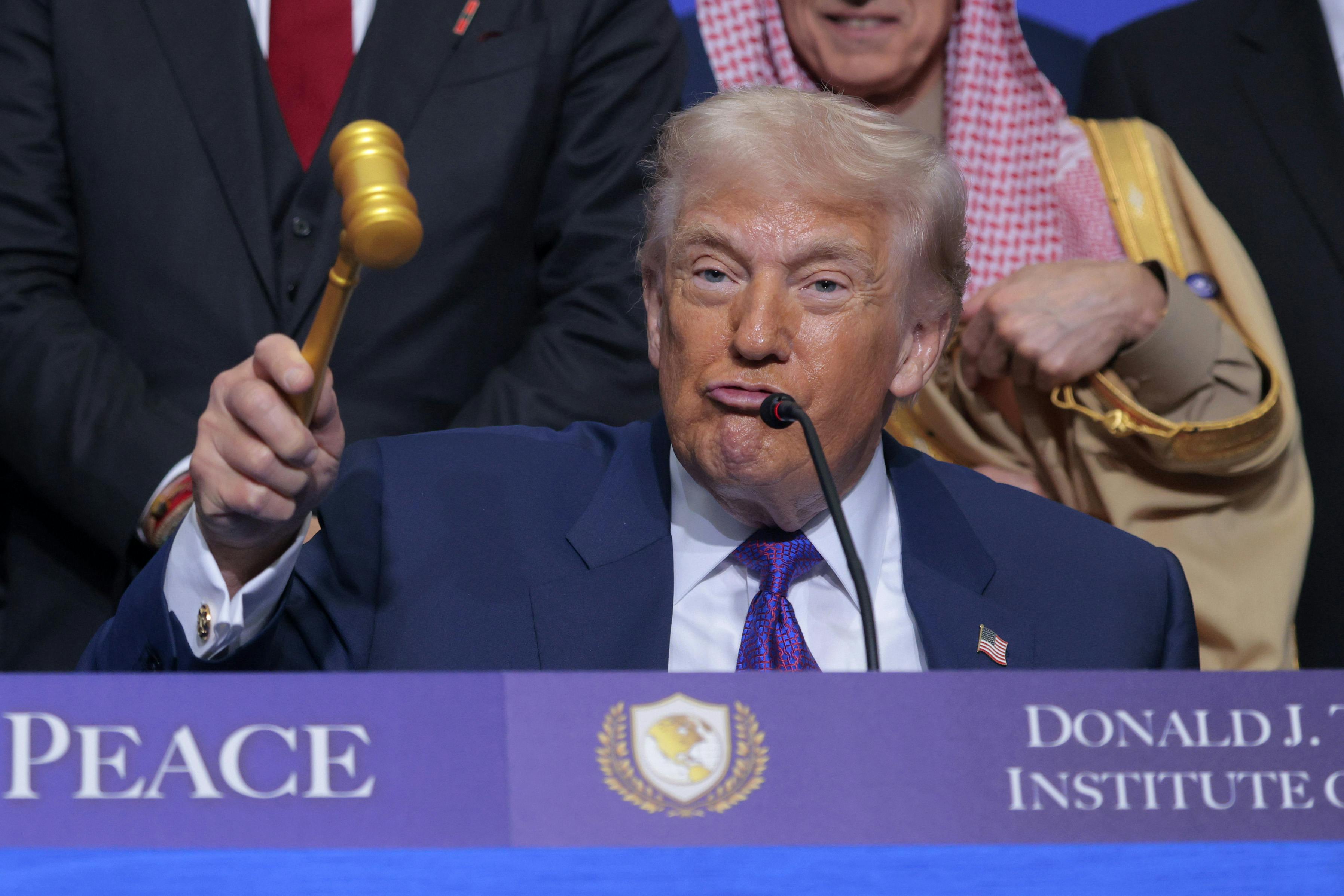 Donald Trump puckers his lips while holding up a gavel