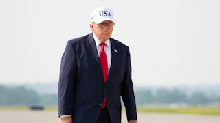 Donald Trump purses his lips while walking on a tarmac