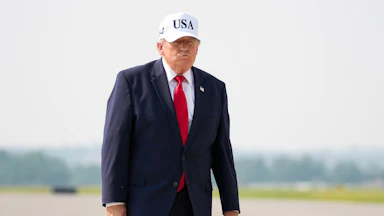 Donald Trump purses his lips while walking on a tarmac
