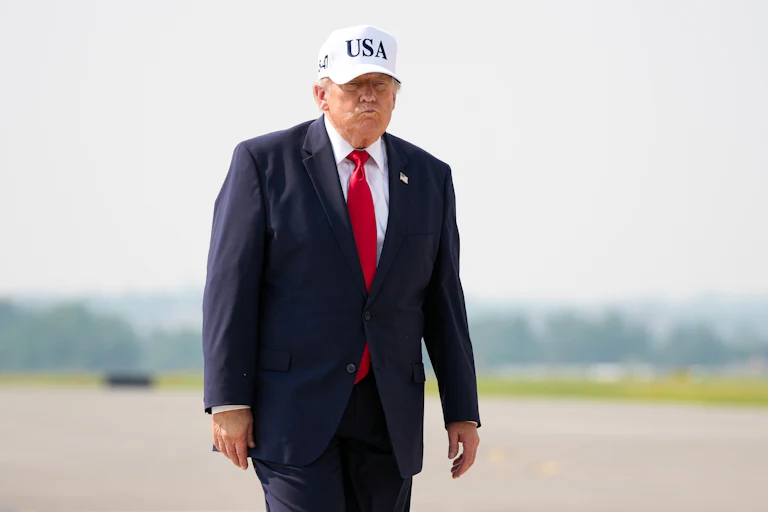 Donald Trump purses his lips while walking on a tarmac