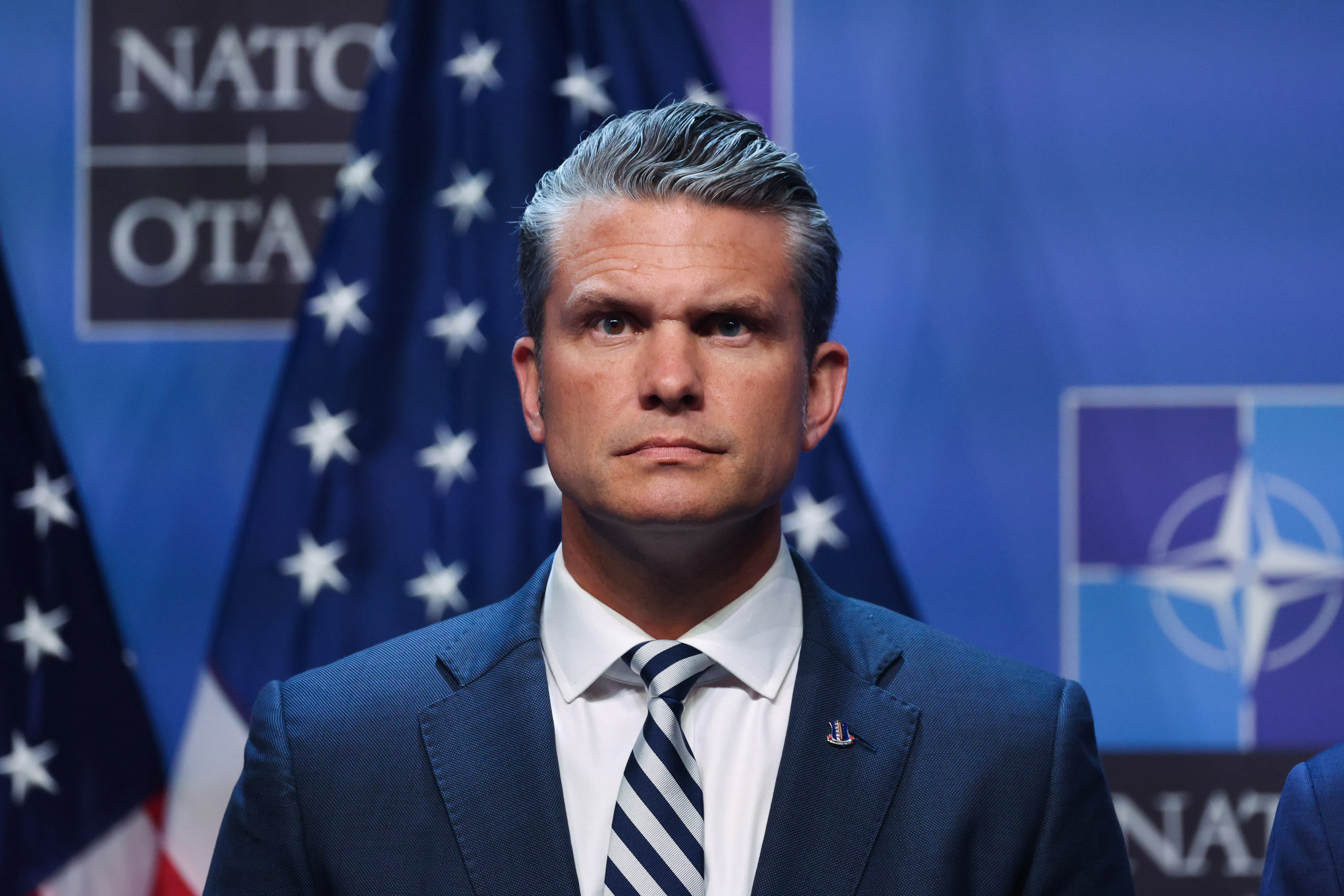 Defense Secretary Pete Hegseth stands on stage during Donald Trump’s press conference at the NATO summit in Turkey