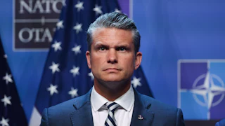 Defense Secretary Pete Hegseth stands on stage during Donald Trump’s press conference at the NATO summit in Turkey