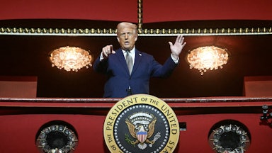 Donald Trump in a Kennedy Center balcony, speaking and pointing at the camera below. The shot makes him seem like a dictator.