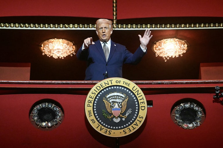 Donald Trump in a Kennedy Center balcony, speaking and pointing at the camera below. The shot makes him seem like a dictator.