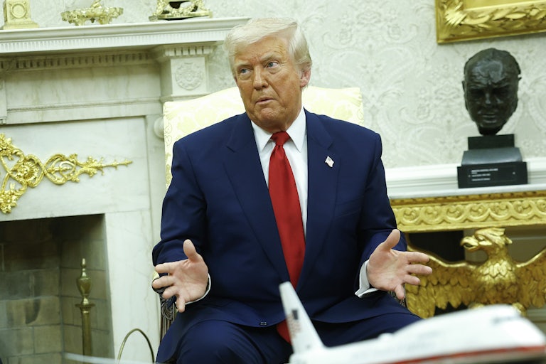 Donald Trump gestures while speaking and sitting in the Oval Office