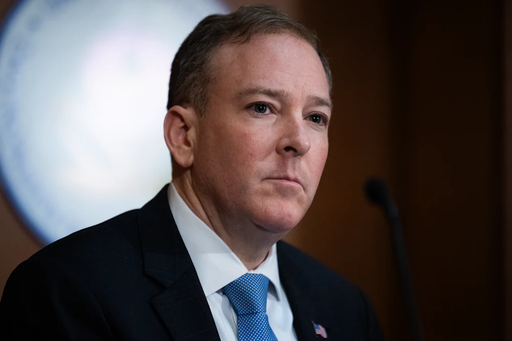 Lee Zeldin is seen wearing a dark suit and light blue tie.