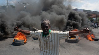 A protester reacts while tires burn in the street during a demonstration following the resignation of its Prime Minister Ariel Henry, in Port-au-Prince, Haiti.