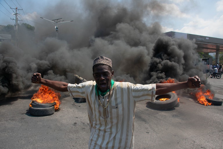 A protester reacts while tires burn in the street during a demonstration following the resignation of its Prime Minister Ariel Henry, in Port-au-Prince, Haiti.