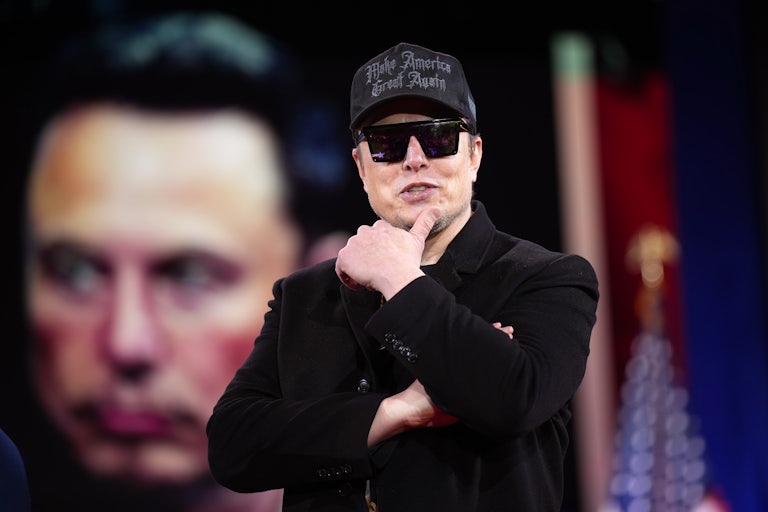 Elon Musk puts his thumb on his chin while speaking onstage at CPAC