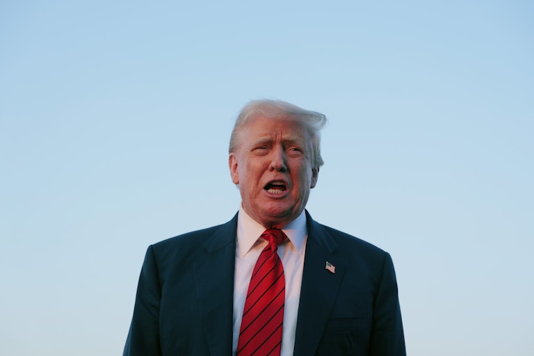 Donald Trump speaks to reporters on an airport tarmac.