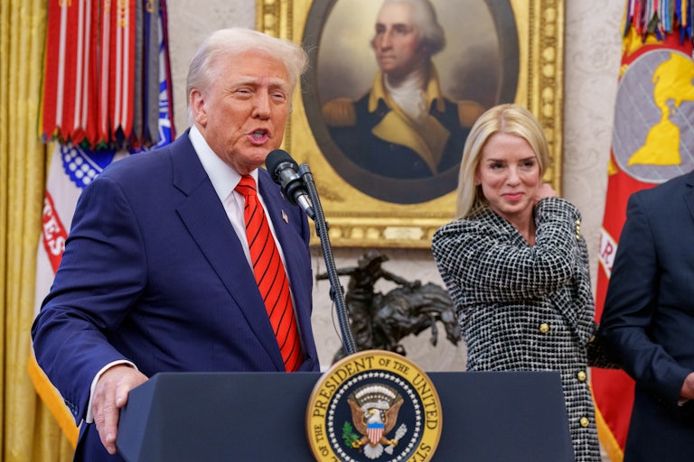 President Donald Trump speaks at the presidential podium while Attorney General Pam Bondi smiles beside him.