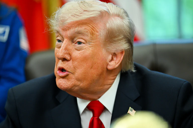 Donald Trump speaks while sitting at his desk in the Oval Office