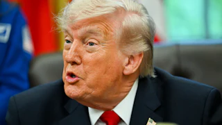 Donald Trump speaks while sitting at his desk in the Oval Office