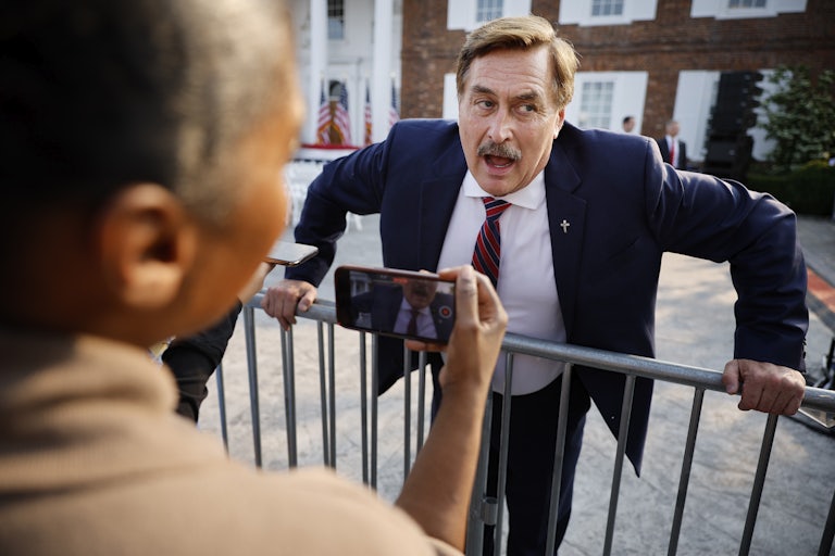 MyPillow CEO Mike Lindell leans over a railing and seems to be fighting with someone