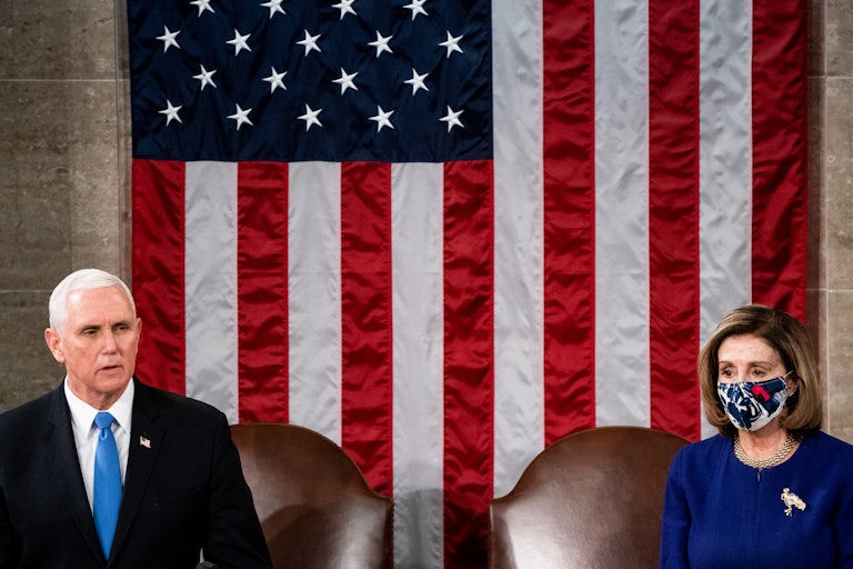 Mike Pence and Nancy Pelosi stand in front of a giant U.S. flag. Pelosi is wearing a face mask and Pence is not.