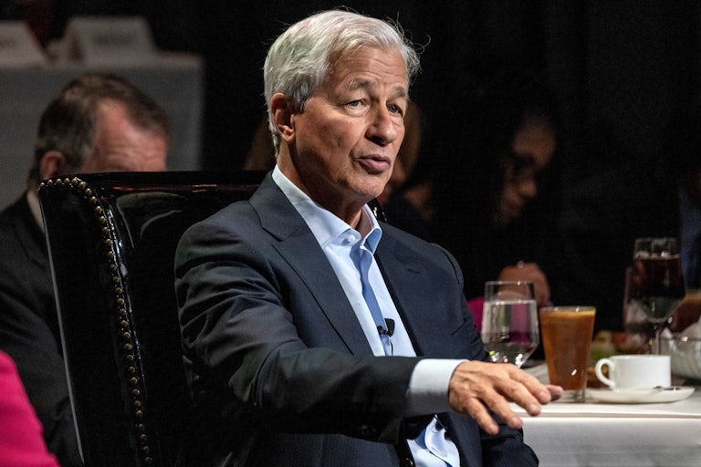 Jamie Dimon speaks while sitting on an armchair. A table is beside him with several cups.