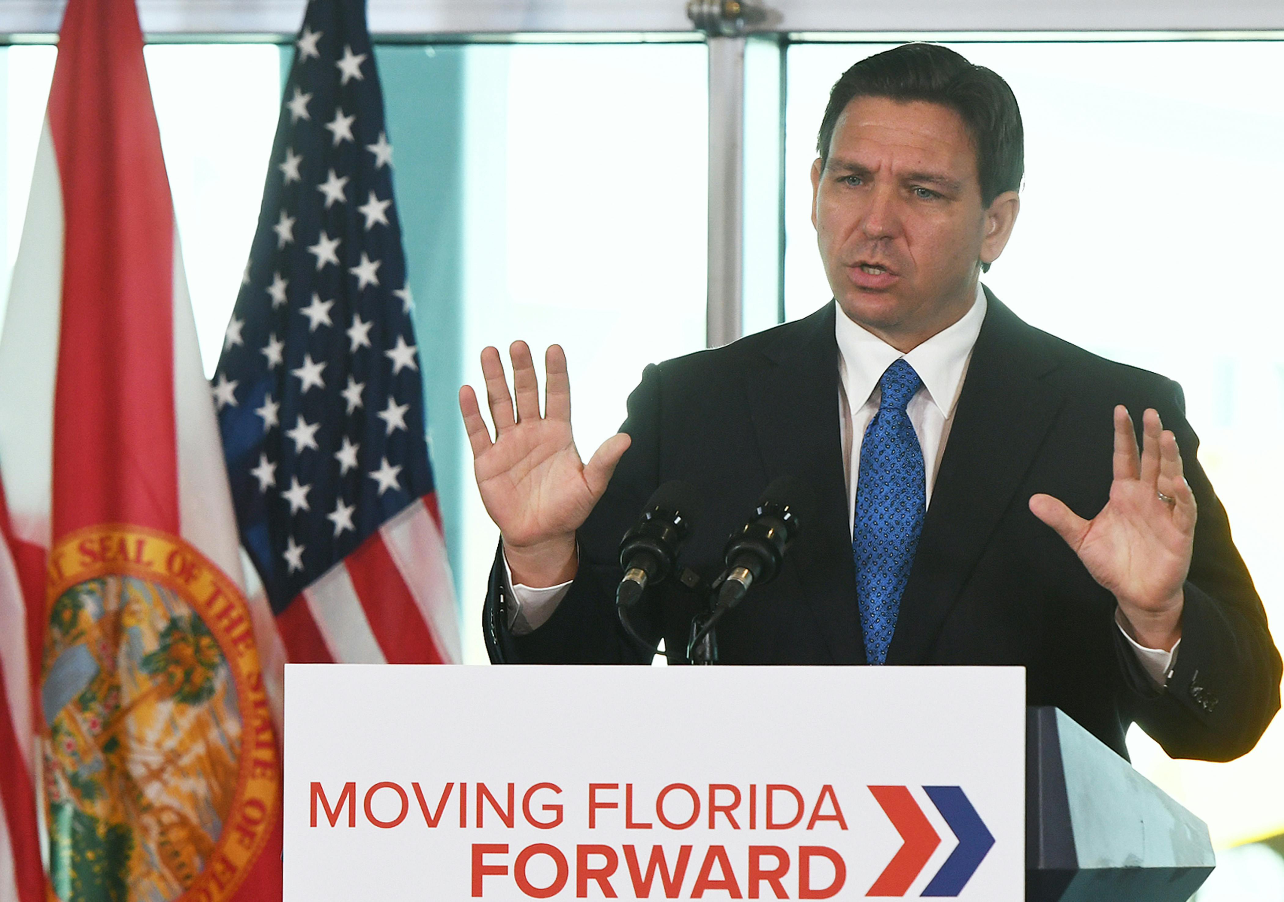Ron DeSantis holds his hands up while speaking.