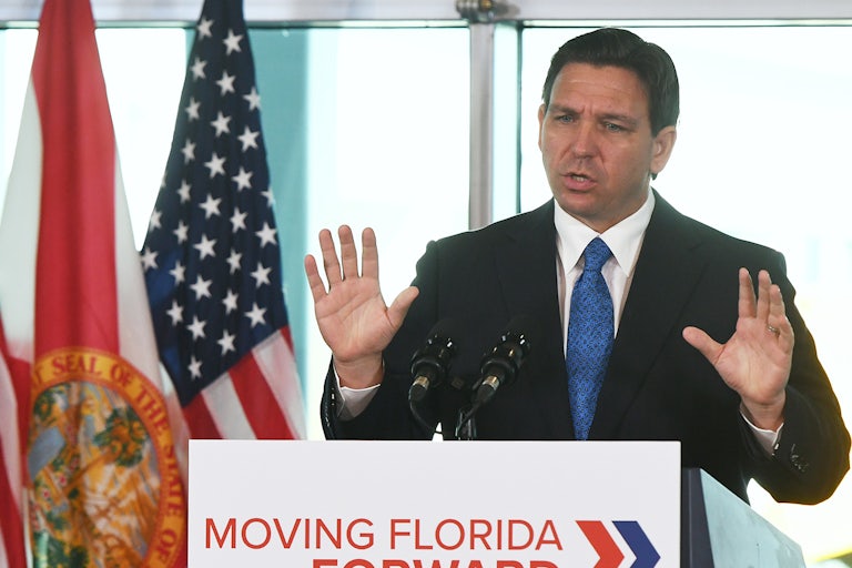 Ron DeSantis holds his hands up while speaking.