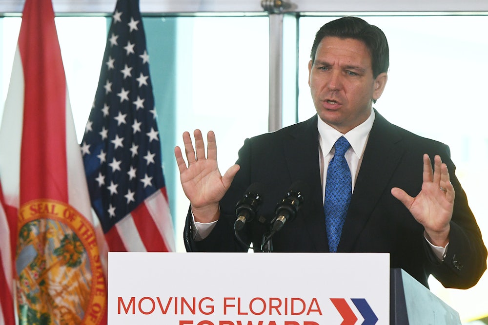 Ron DeSantis holds his hands up while speaking.
