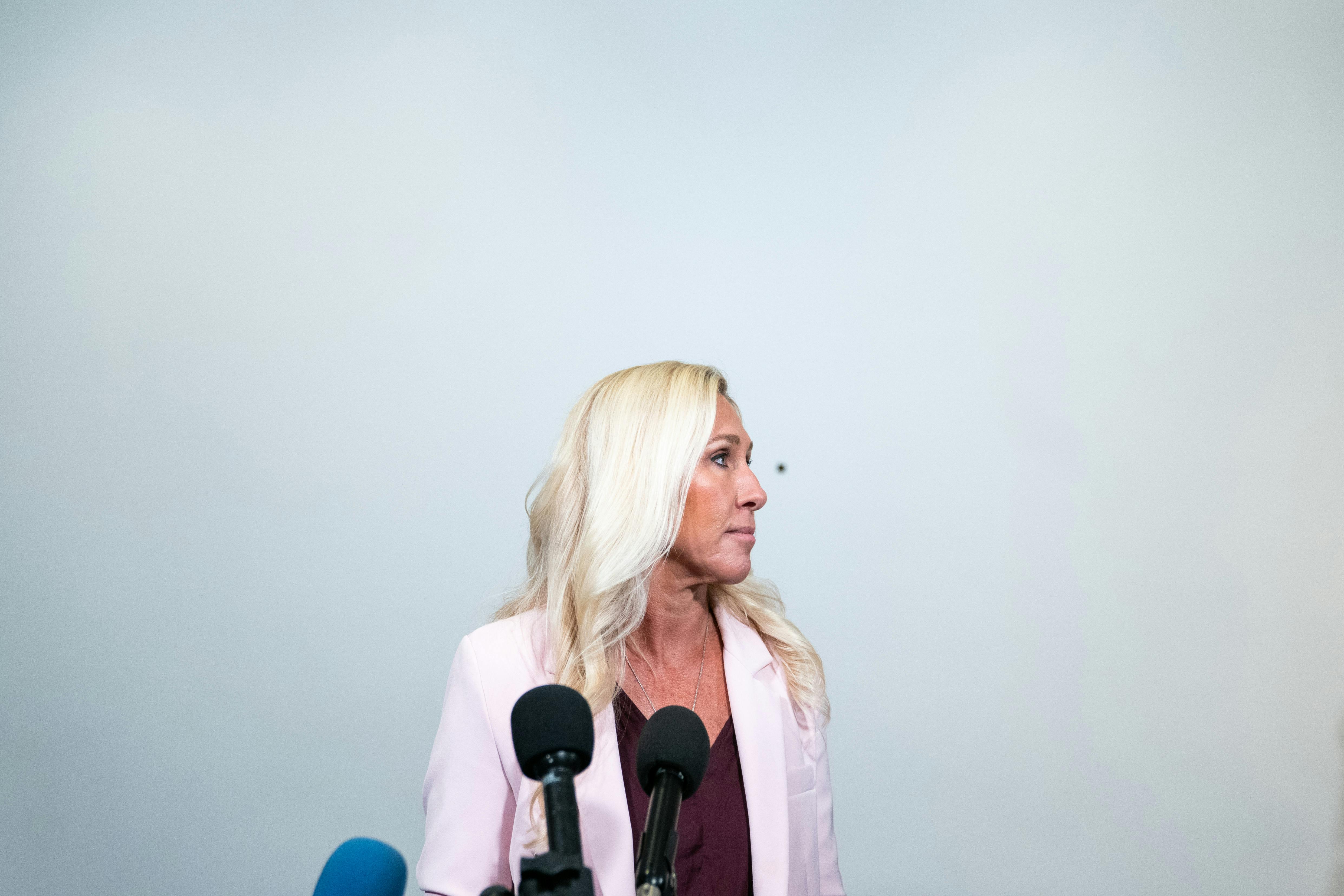Marjorie Taylor Greene stands at a press conference.