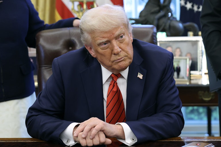 Donald Trump sits at his desk in the Oval Office of the White House.