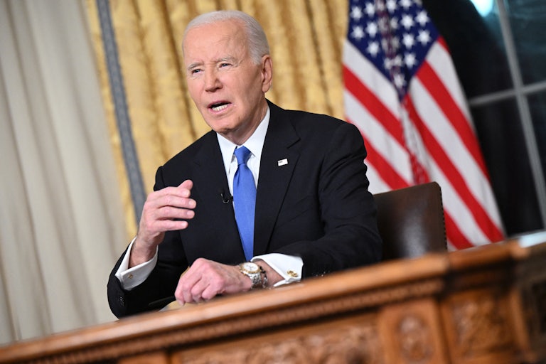 Joe Biden sits in the Oval Office and speaks