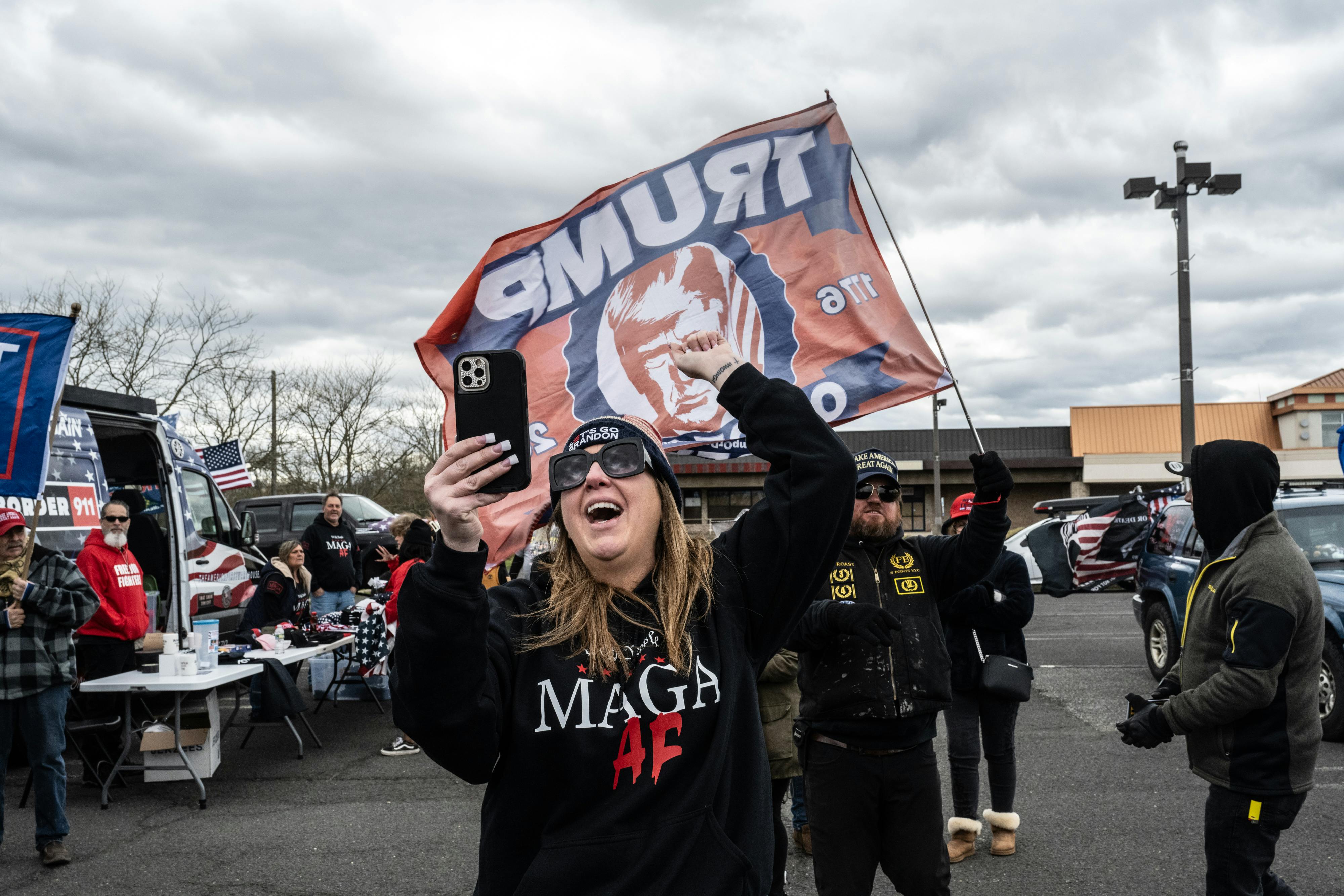 far right supporters hold banners featuring Donald Trump's face and yell and scream