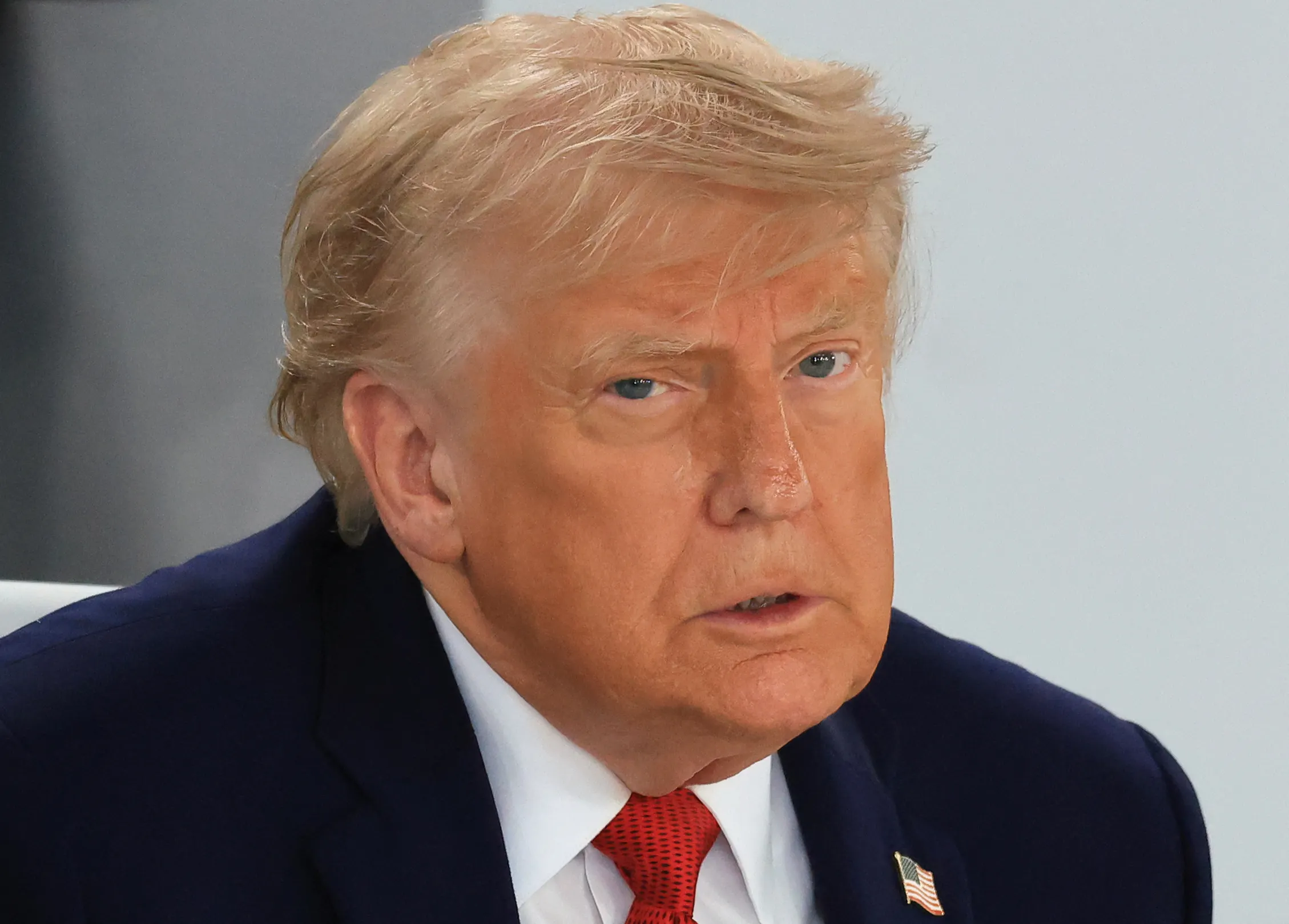 Donald Trump frowns while sitting at a meeting at the G7 summit