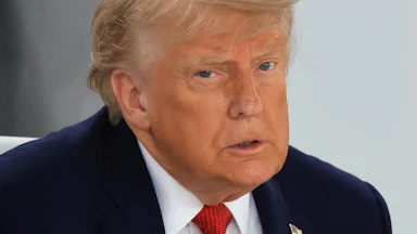 Donald Trump frowns while sitting at a meeting at the G7 summit