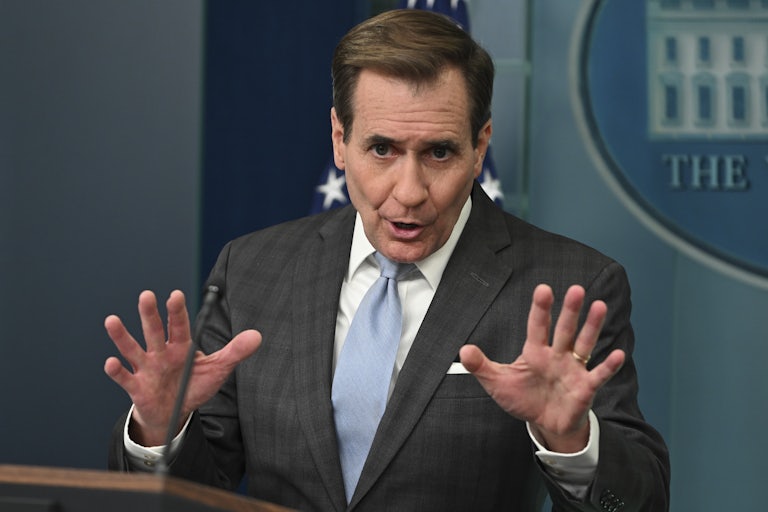 John Kirby speaks and splays his hands out as if in anger. He is giving a press briefing judging by the White House logo in the background.