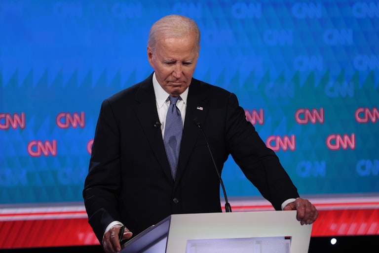 Joe Biden at the CNN debate holds his arms on the podium and looks downward, as if defeated