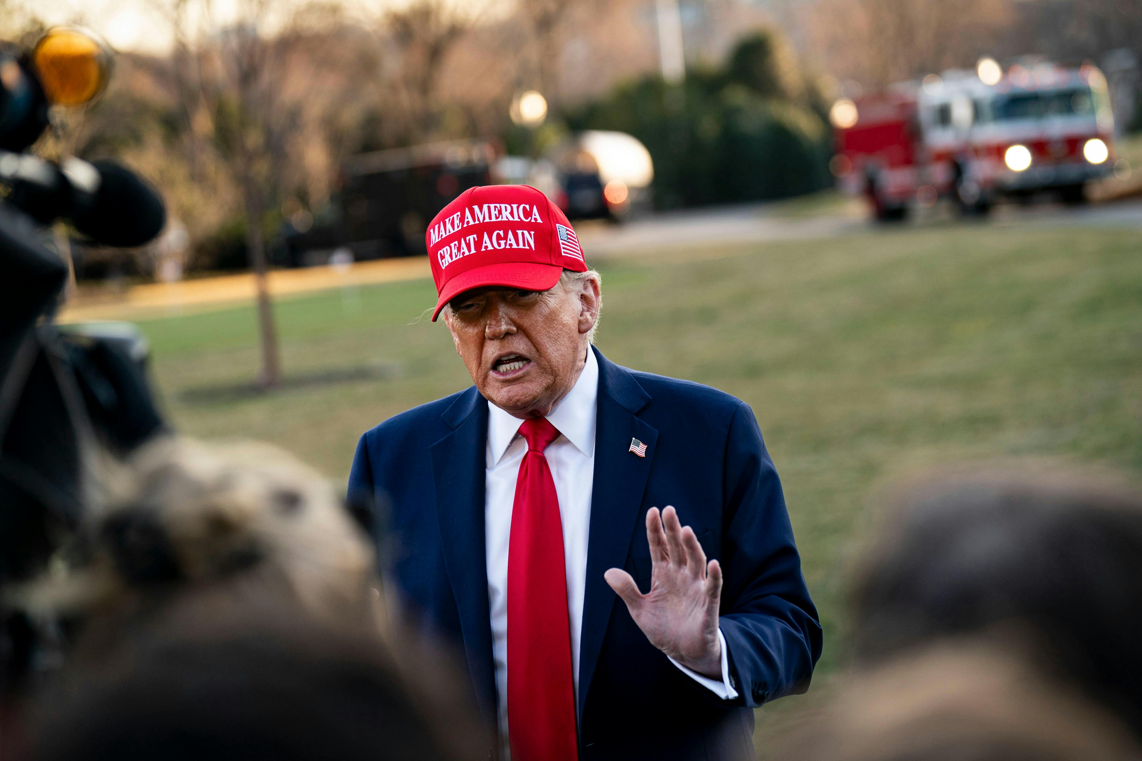 Trump gesticulates while talking and wearing a "Make America Great Again" hat.